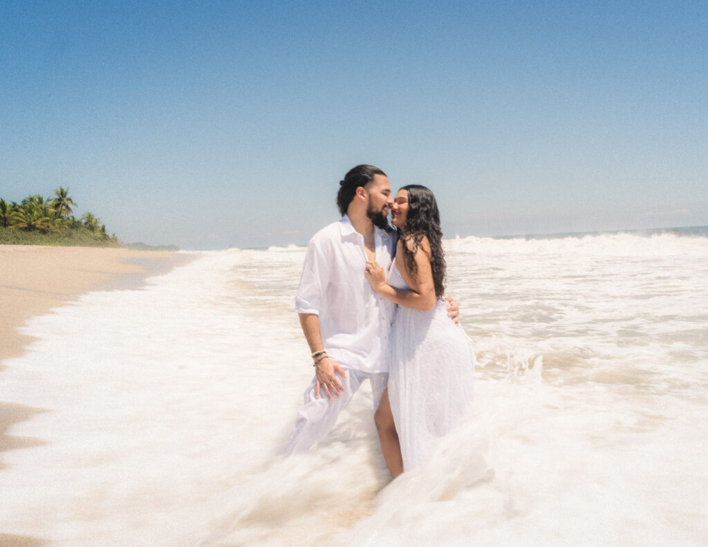 A joyful moment as the bride and groom embrace in the ocean waves during their intimate elopement in Tayrona National Park. Ein freudiger Moment, als Braut und Bräutigam sich in den Wellen des Ozeans während ihres intimen Elopements im Tayrona-Nationalpark umarmen.