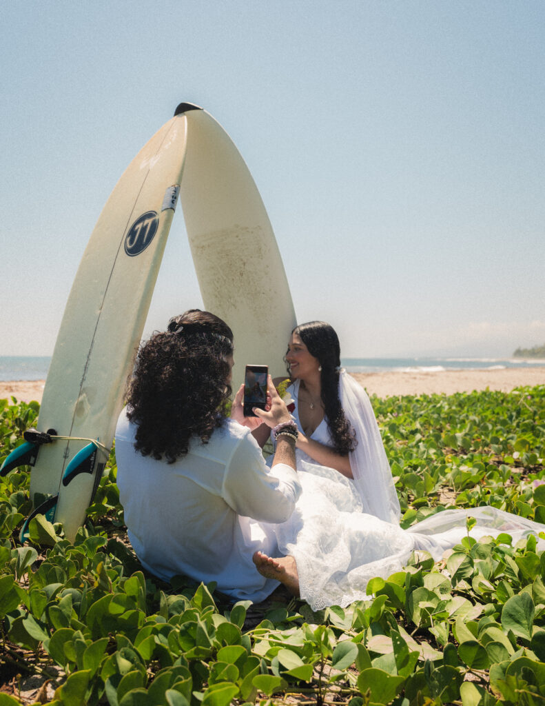 A heartfelt moment between the bride and groom under a surfboard, capturing their love amidst the stunning greenery of Tayrona National Park in Colombia. Ein emotionaler Moment zwischen Braut und Bräutigam unter einem Surfbrett, eingefangen in der atemberaubenden Natur des Tayrona-Nationalparks in Kolumbien.