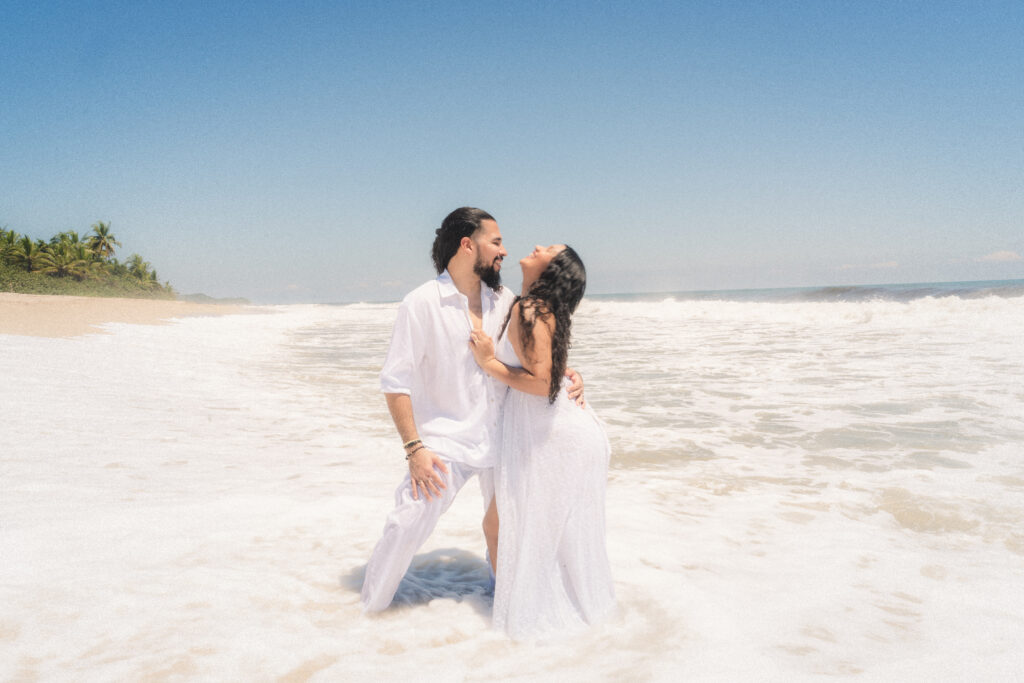 The couple shares laughter while embracing in the ocean, creating timeless memories during their elopement in Tayrona National Park. Das Paar lacht gemeinsam und umarmt sich im Ozean, während es zeitlose Erinnerungen bei ihrem Elopement im Tayrona-Nationalpark schafft.